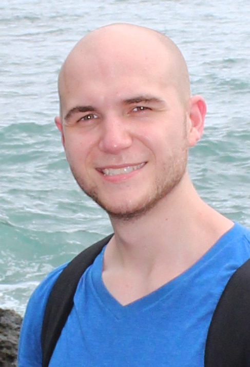 Former Ph.D. student Eric Johnston stands on a cliff with the sea behind him. (Photo Courtesy: Eric Johnston)
