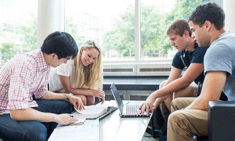 A group of students sitting around a laptop