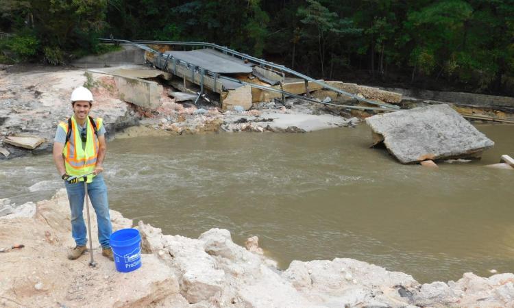 Man testing soil quality by a failed dam