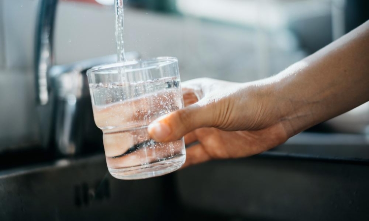 A hand filling a glass with water from a tap