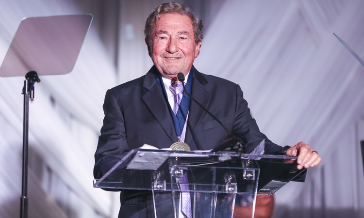 A smiling man stands at a podium 