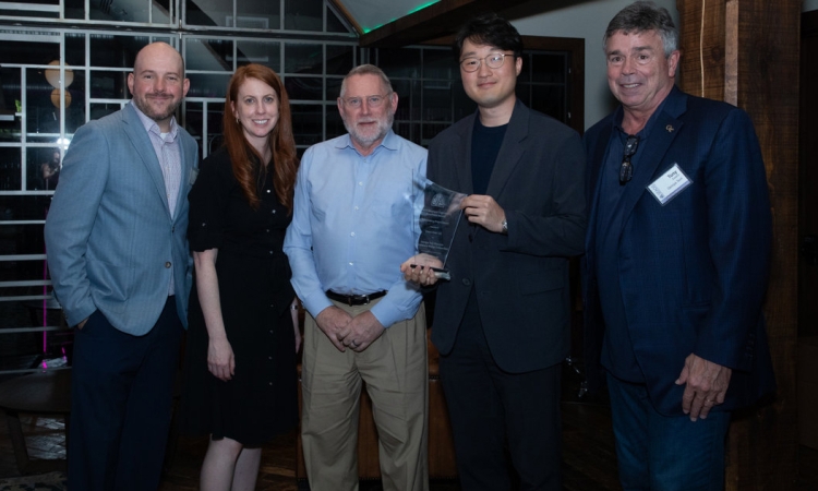 Five people pose with a glass award 