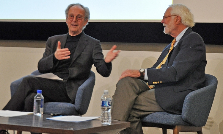 Two men sitting side by side in blue chairs 