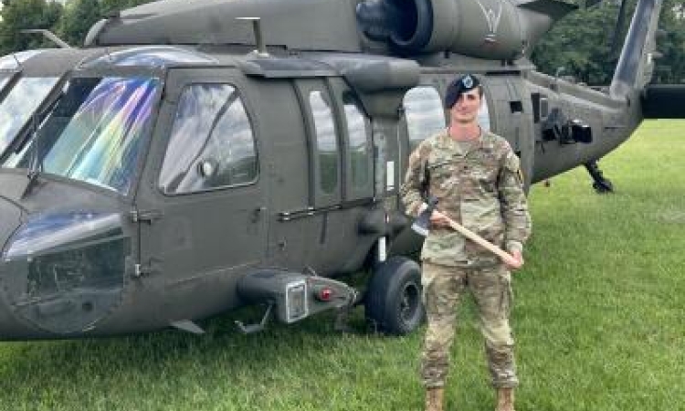 Mason Ladd in infantry military uniform standing in front of a military helicopter
