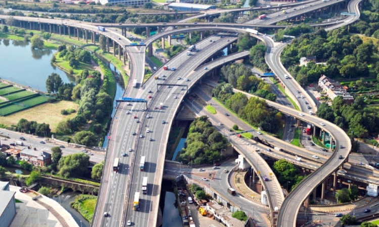 Cars and trucks drive on an interchange with roads branching off in several directions.