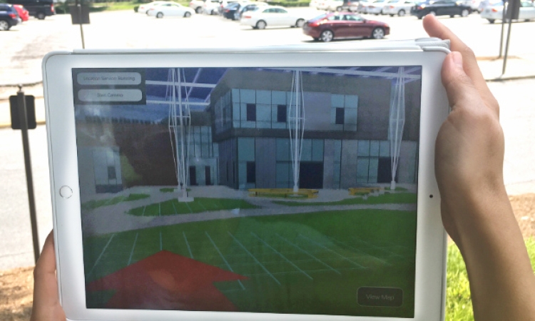 Using an iPad and an augmented reality model like this, students and other future users of Georgia Tech's Living Building will be able to tour the facility long before it opens, offering input on some of the design decisions. A user shows how the model will work at the future site of the building. (Photo Courtesy: Kendeda Fund Living Building Chronicle)