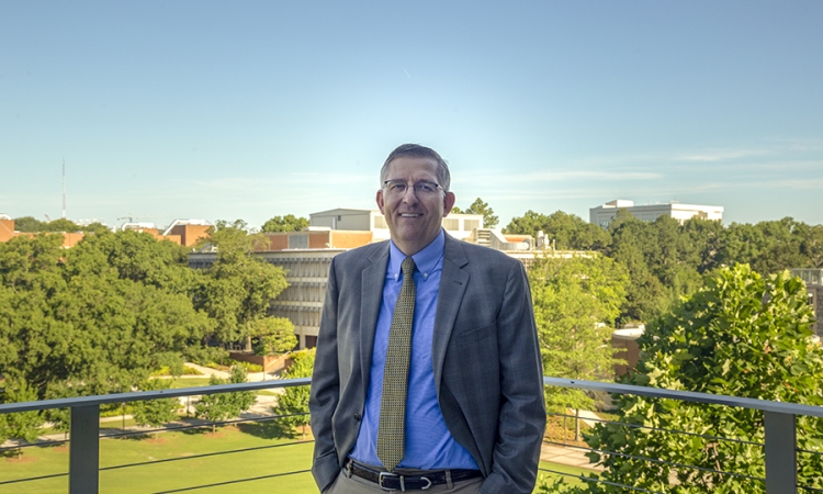 Donald Webster, Karen and John Huff Chair of the School of Civil and Environmental Engineering, poses with Tech Green in the background.