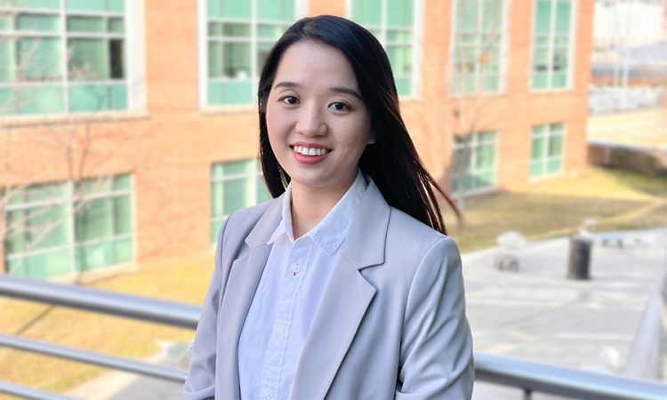 Wensi Chen poses in front of a brick building for a portrait 