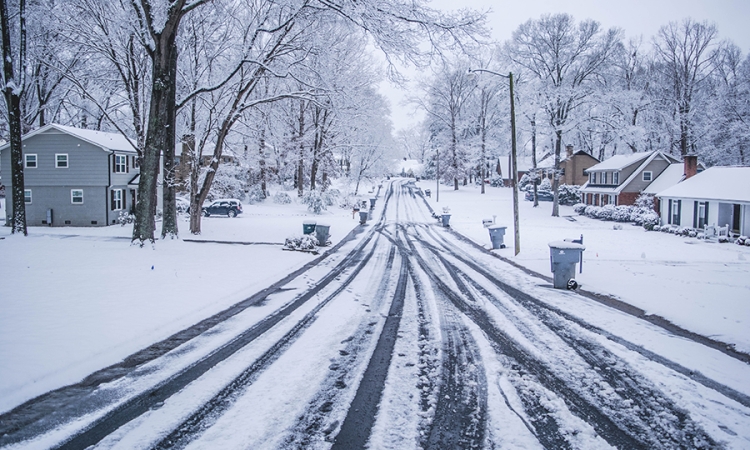 A snowy residential street with gray skies 