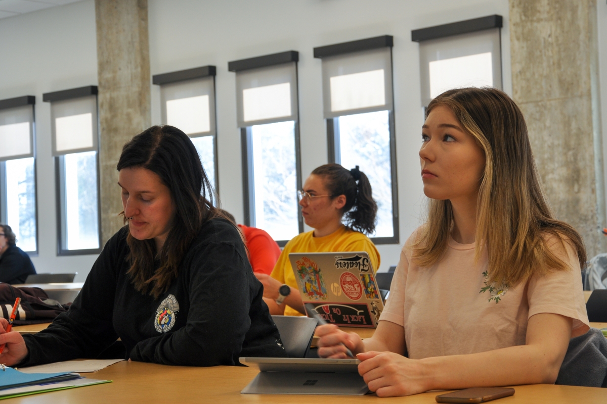 two students sit at a desk in a classroom 