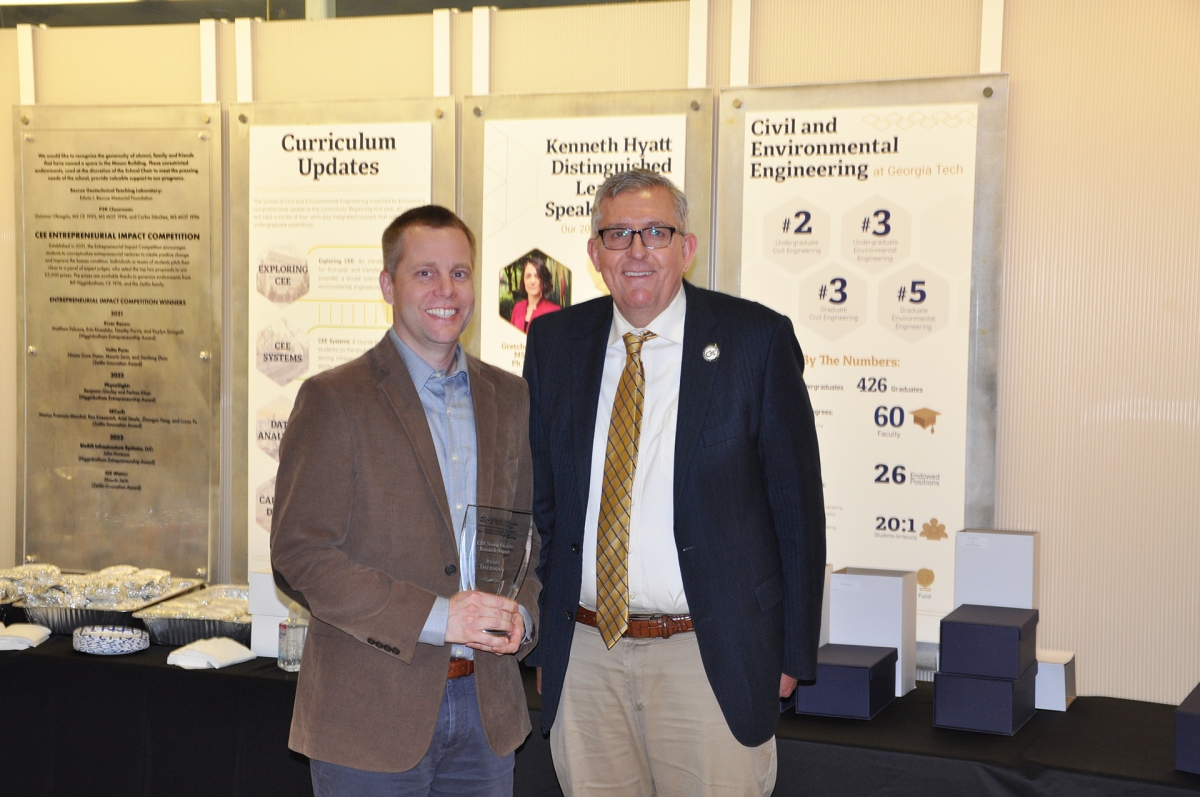 Portrait of Professor Ryan Sherman holding award with Chair Don Webster