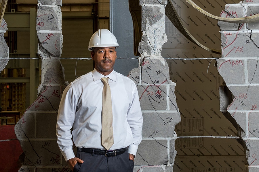 Reginald DesRoches stands with the ruptured cinder block wall one of his Ph.D. students destroyed while testing different kinds of masonry infill designed to strengthen similar structures in the Caribbean. DesRoches will draw on decades of earthquake research like this for the University of California, Davis, College of Engineering distinguished lecture he'll deliver in September. (Photo: Rob Felt)