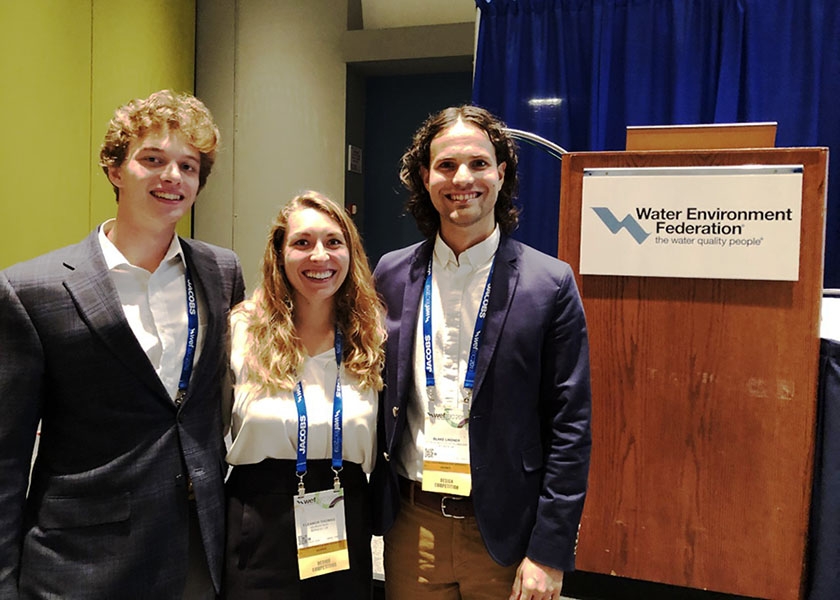 Three Georgia Tech students stand by the podium at the Water Environment Federation's student design competition